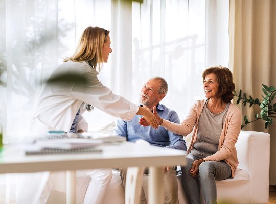 Young female doctor talking to a senior couple. Home visit.
